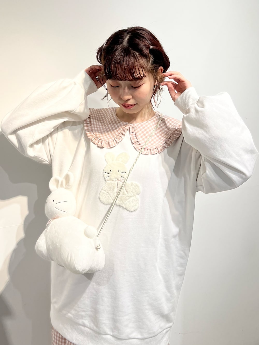 ホワイト系のショルダーバッグ、ピンク系のワンピース、ホワイト系のスウェットを着用したレディースの冬コーディネートの7枚目の写真