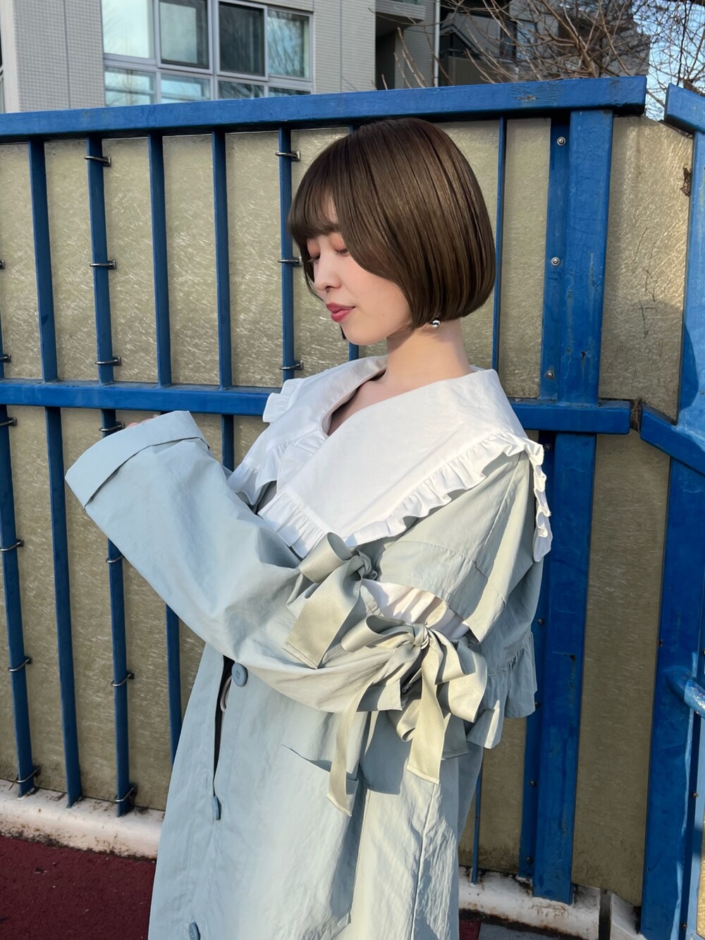 ブルー系のトレンチコート、ホワイト系のシャツ/ブラウス、ベージュ系のブーツを着用したレディースの冬コーディネートの6枚目の写真