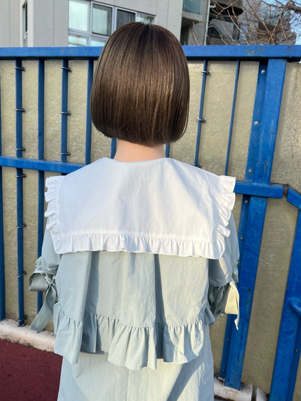 ブルー系のトレンチコート、ホワイト系のシャツ/ブラウス、ベージュ系のブーツを着用したレディースの冬コーディネートの7枚目の写真