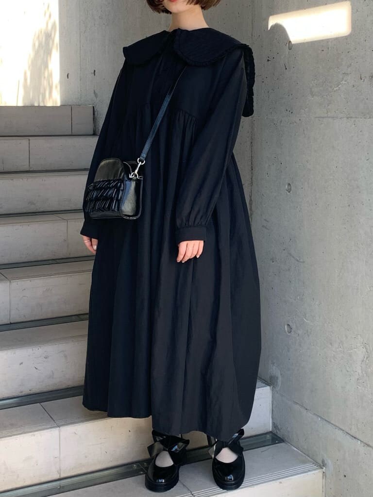 ブラック系のパンプス、ブラック系のワンピース、ブラック系のショルダーバッグを着用したレディースの冬コーディネートの3枚目の写真
