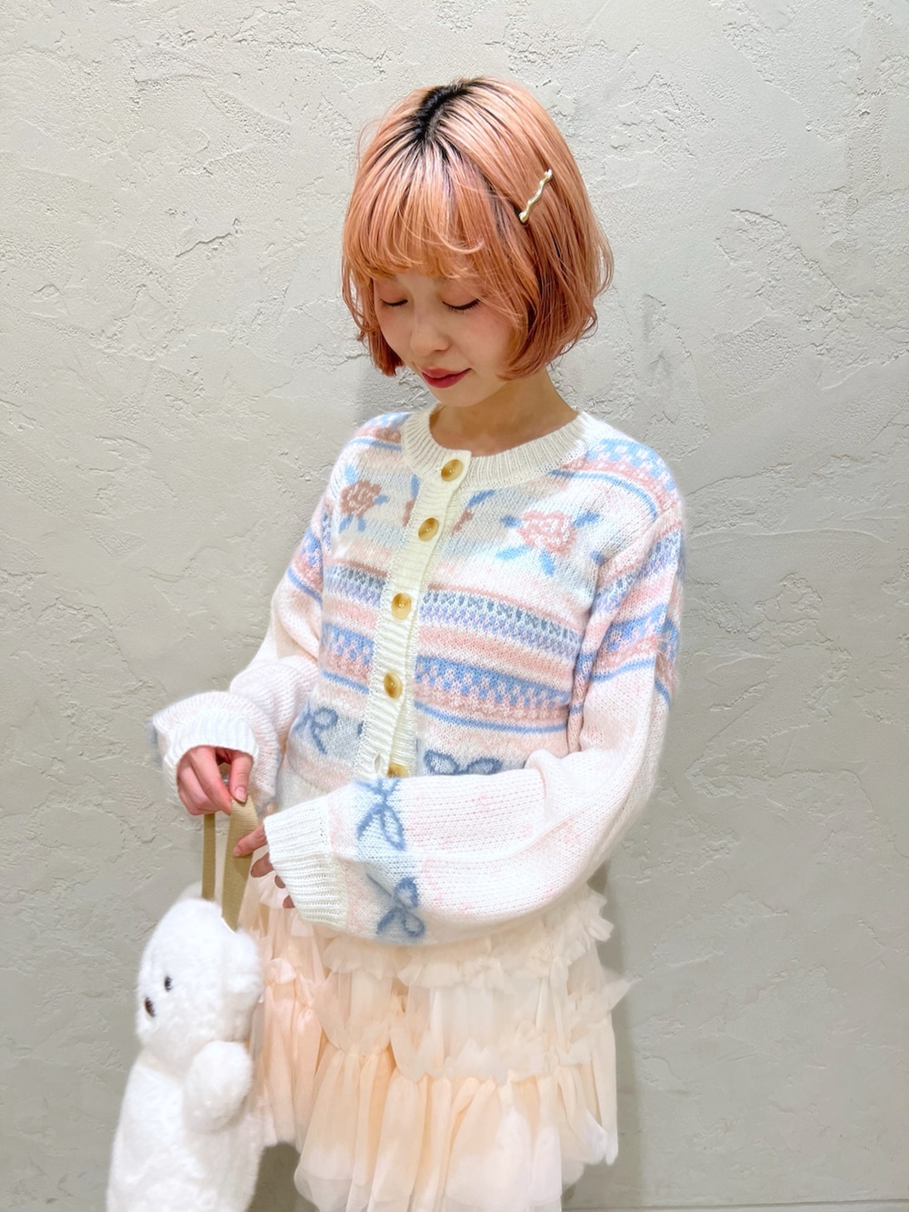 ホワイト系のカーディガン/ボレロ、ピンク系のスカート、ホワイト系のハンドバッグを着用したレディースの秋コーディネートの6枚目の写真