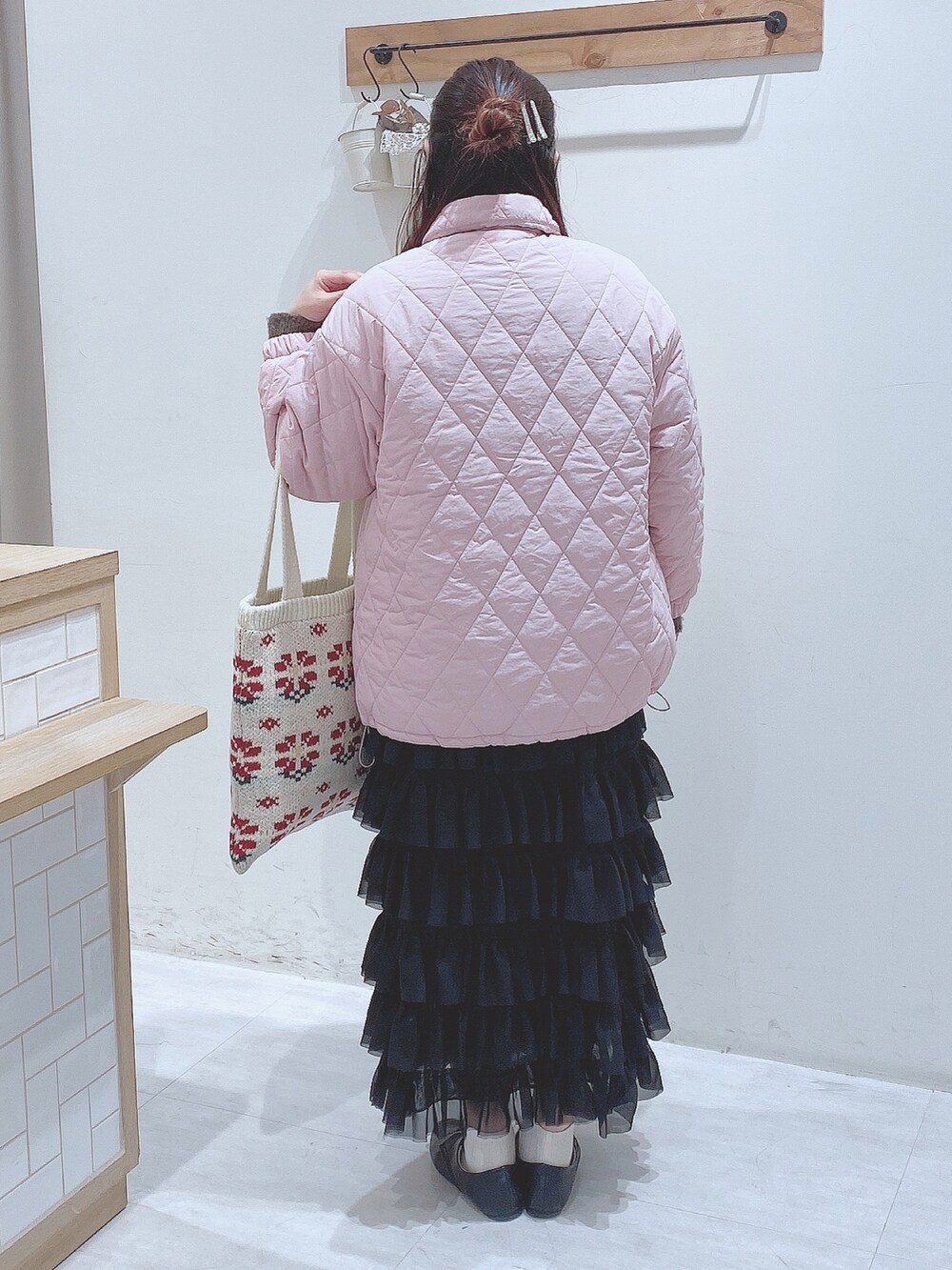 ブラック系のスカート、グリーン系のニット/セーター、ピンク系のノーカラージャケットを着用したレディースの冬コーディネートの3枚目の写真