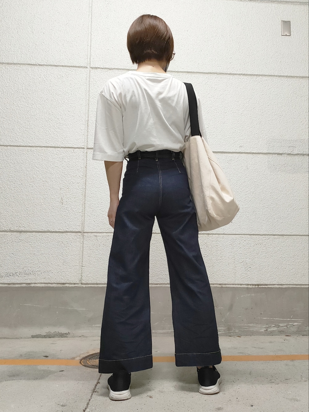 ホワイト系のTシャツ/カットソー、ブルー系のデニムパンツ、ベージュ系のトートバッグを着用したメンズの秋コーディネートの2枚目の写真