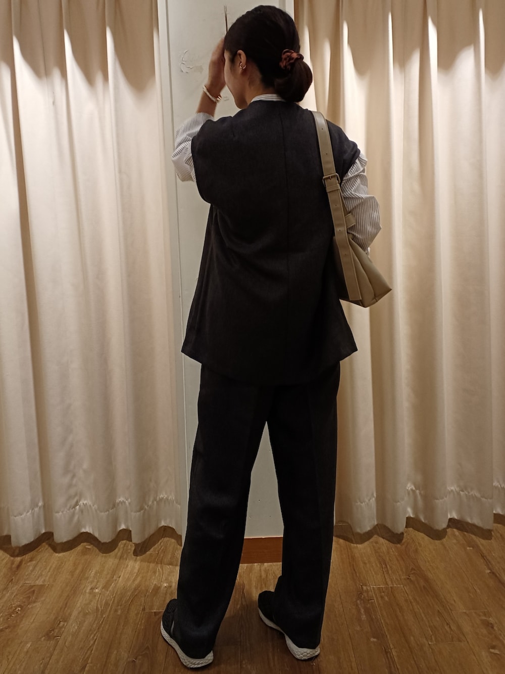 ホワイト系のショルダーバッグ、グレー系のベスト、グレー系のその他パンツを着用したレディースの秋コーディネートの2枚目の写真