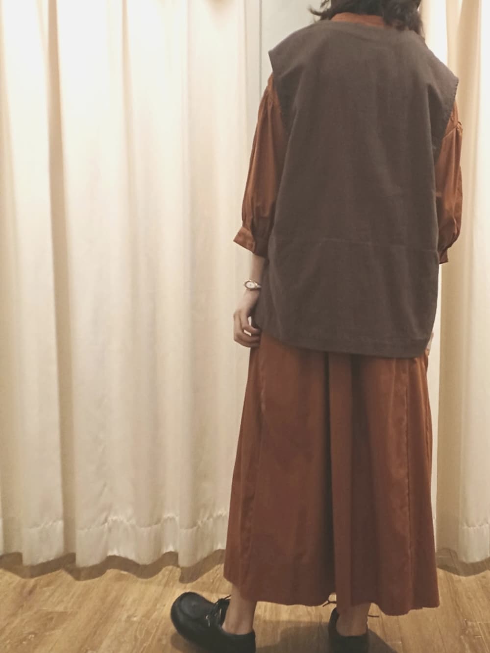 ブラウン系のベスト、オレンジ系のワンピース、ブラック系のその他シューズを着用したレディースの秋コーディネートの3枚目の写真