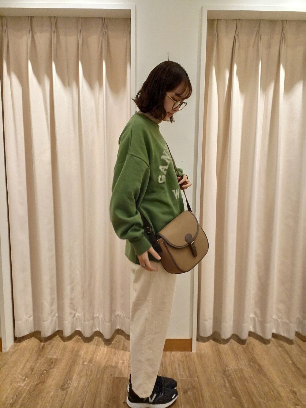 グリーン系のTシャツ/カットソー、ブラウン系のニット/セーター、ブラウン系のショルダーバッグを着用したレディースの秋コーディネートの2枚目の写真