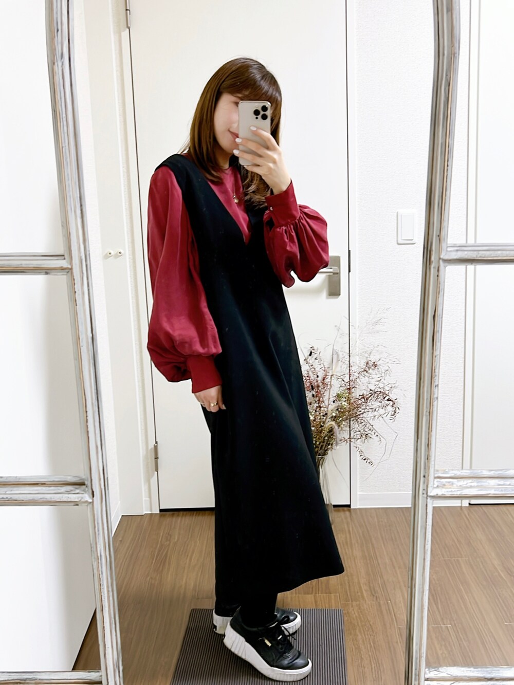 レッド系のシャツ/ブラウス、ブラック系のジャンパースカート、ブラック系のスニーカーを着用したレディースの冬コーディネートの2枚目の写真