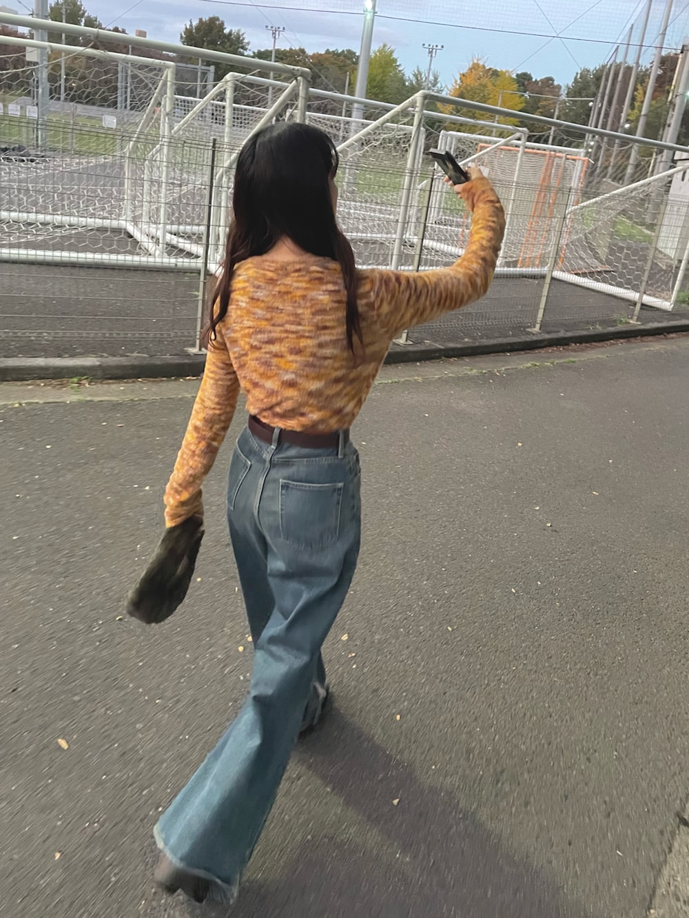 ブルー系のデニムパンツ、オレンジ系のTシャツ/カットソーを着用したレディースの秋コーディネートの2枚目の写真