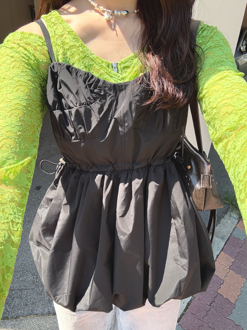 ブルー系のデニムパンツ、グリーン系のスニーカー、ブラック系のチュニックを着用したレディースの秋コーディネートの2枚目の写真