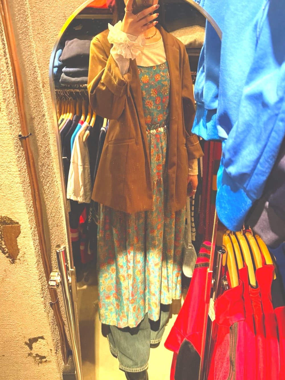 ブラウン系のテーラードジャケット、ブルー系のデニムパンツ、グリーン系のワンピースを着用したレディースの秋コーディネートの2枚目の写真