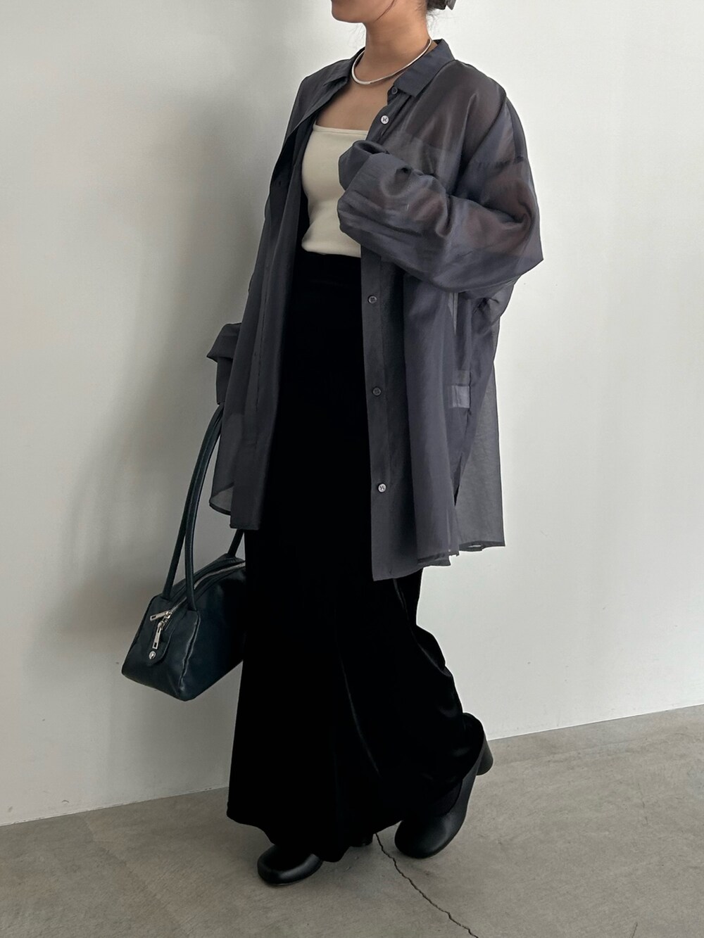 ブラック系のスカート、ブラック系のサンダル、ブルー系のボストンバッグを着用したレディースの春コーディネートの2枚目の写真