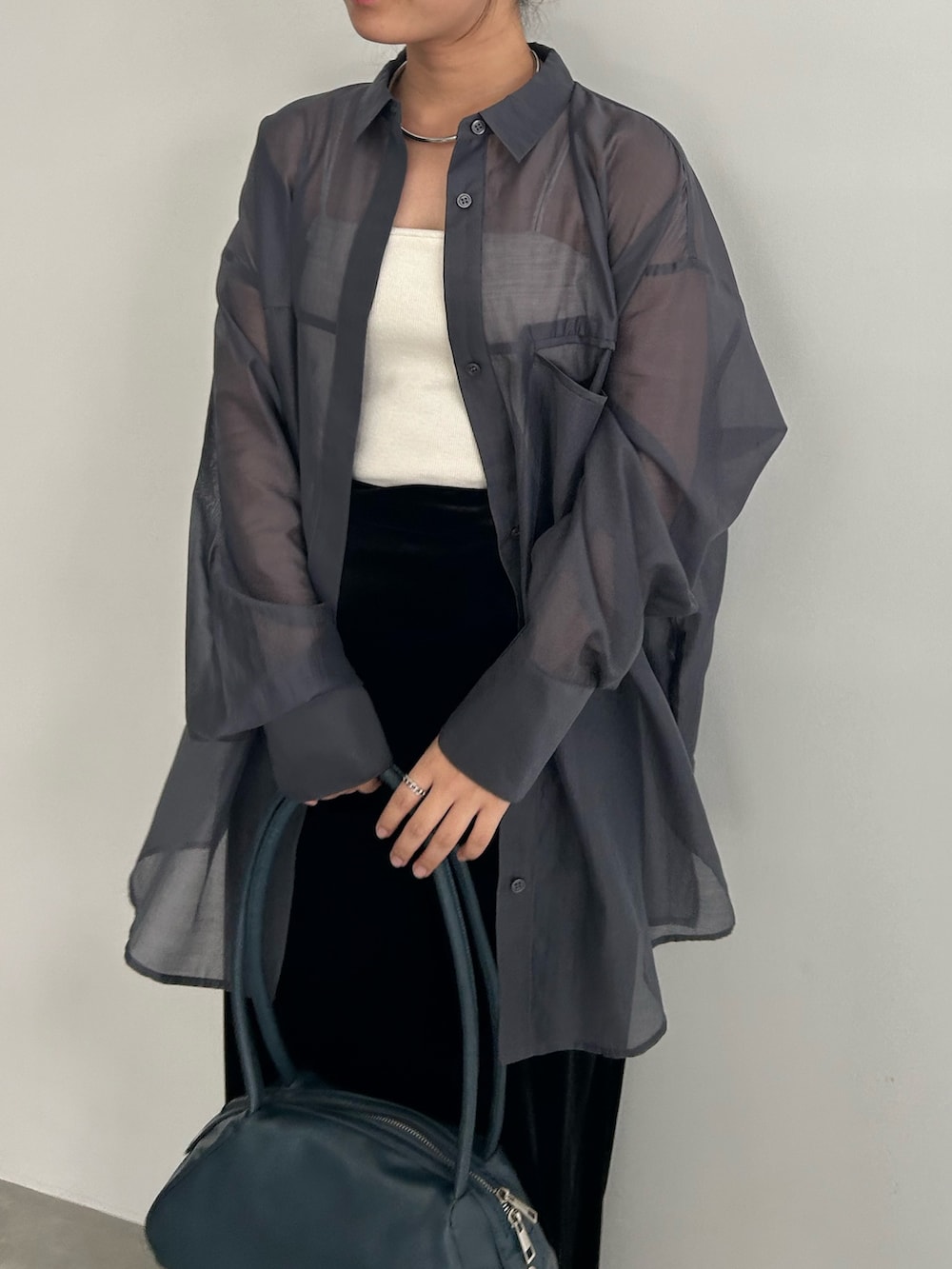 ブラック系のスカート、ブラック系のサンダル、ブルー系のボストンバッグを着用したレディースの春コーディネートの4枚目の写真