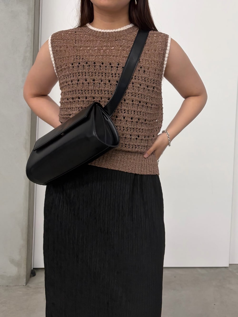 ブラック系のスカート、ブラック系のショルダーバッグ、ブラウン系のニット/セーターを着用したレディースの夏コーディネートの4枚目の写真