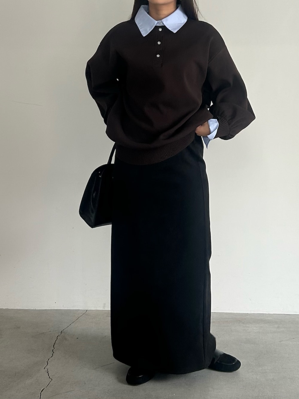 ブラック系のスカート、ブラック系のハンドバッグ、ブラウン系のニット/セーターを着用したレディースの秋コーディネートの5枚目の写真