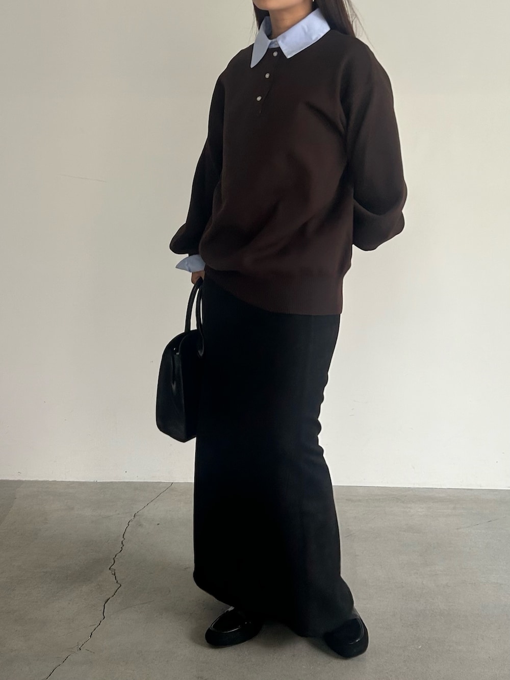 ブラック系のスカート、ブラック系のハンドバッグ、ブラウン系のニット/セーターを着用したレディースの秋コーディネートの6枚目の写真