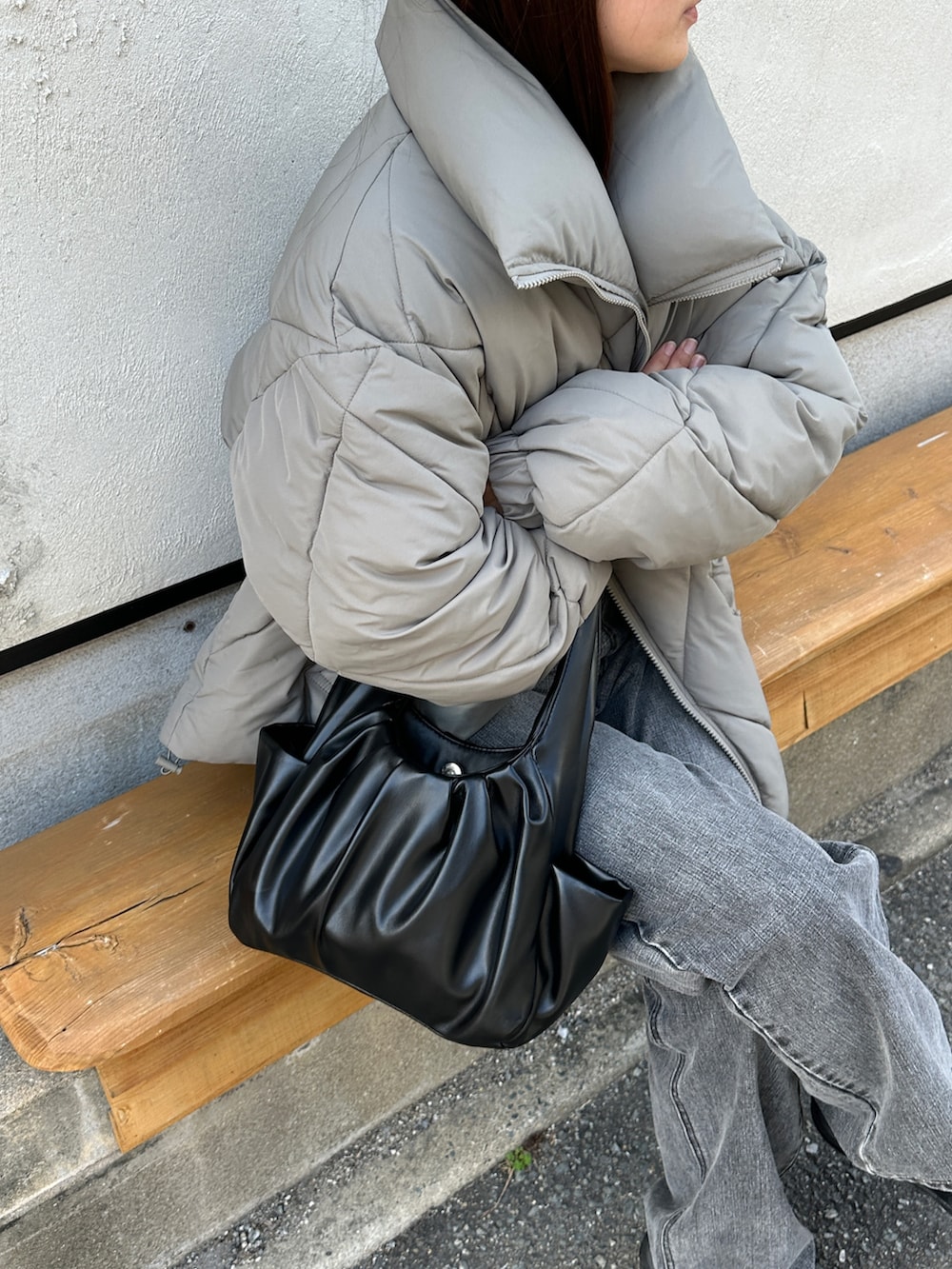 グリーン系のダウンジャケット/コート、ブラック系のハンドバッグ、ブラック系のデニムパンツを着用したレディースの秋コーディネートの3枚目の写真