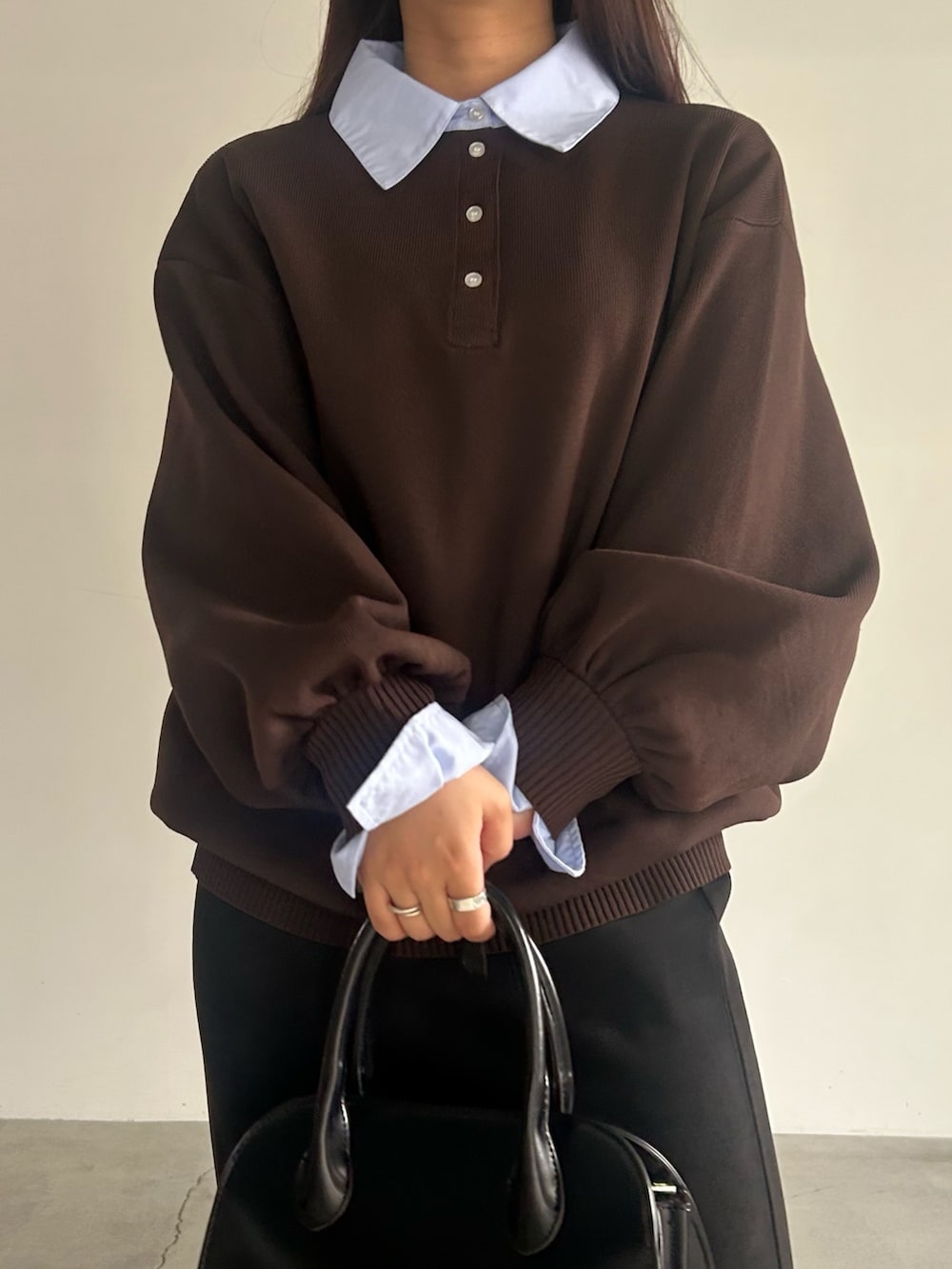 ブラック系のスカート、ブラック系のハンドバッグ、ブラウン系のニット/セーターを着用したレディースの秋コーディネートの4枚目の写真