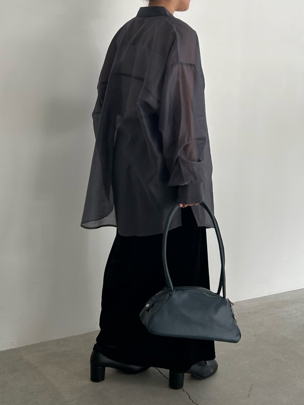 ブラック系のスカート、ブラック系のサンダル、ブルー系のボストンバッグを着用したレディースの春コーディネートの7枚目の写真