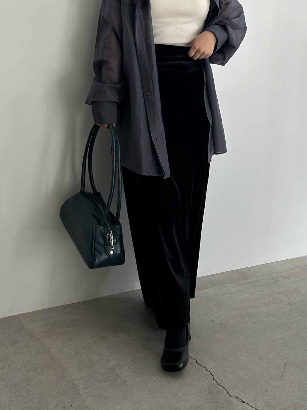 ブラック系のスカート、ブラック系のサンダル、ブルー系のボストンバッグを着用したレディースの春コーディネートの3枚目の写真