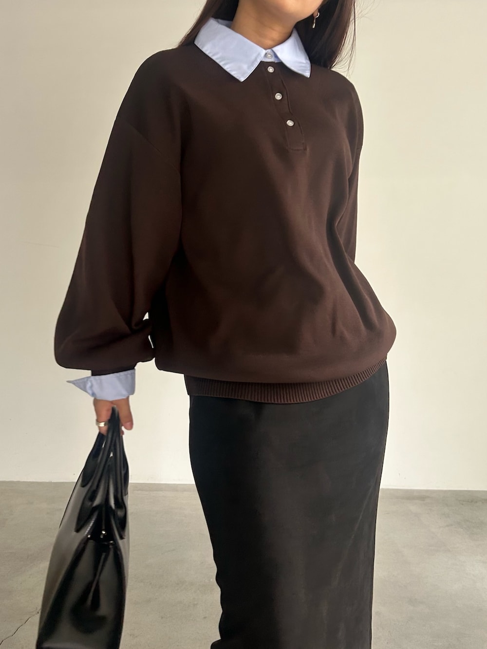 ブラック系のスカート、ブラック系のハンドバッグ、ブラウン系のニット/セーターを着用したレディースの秋コーディネートの3枚目の写真