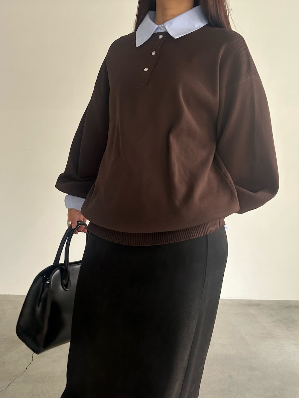 ブラック系のスカート、ブラック系のハンドバッグ、ブラウン系のニット/セーターを着用したレディースの秋コーディネートの2枚目の写真