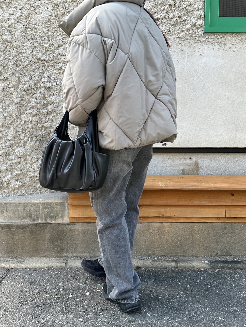 グリーン系のダウンジャケット/コート、ブラック系のハンドバッグ、ブラック系のデニムパンツを着用したレディースの秋コーディネートの4枚目の写真