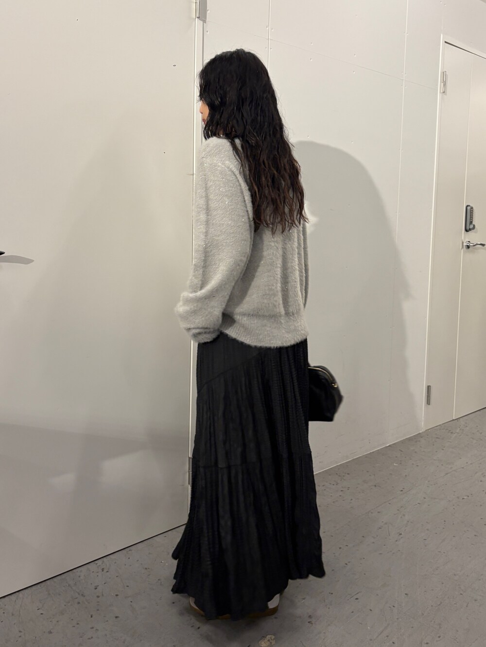 グレー系のニット/セーター、ブラック系のスカート、ブラック系のショルダーバッグを着用したレディースの秋コーディネートの3枚目の写真