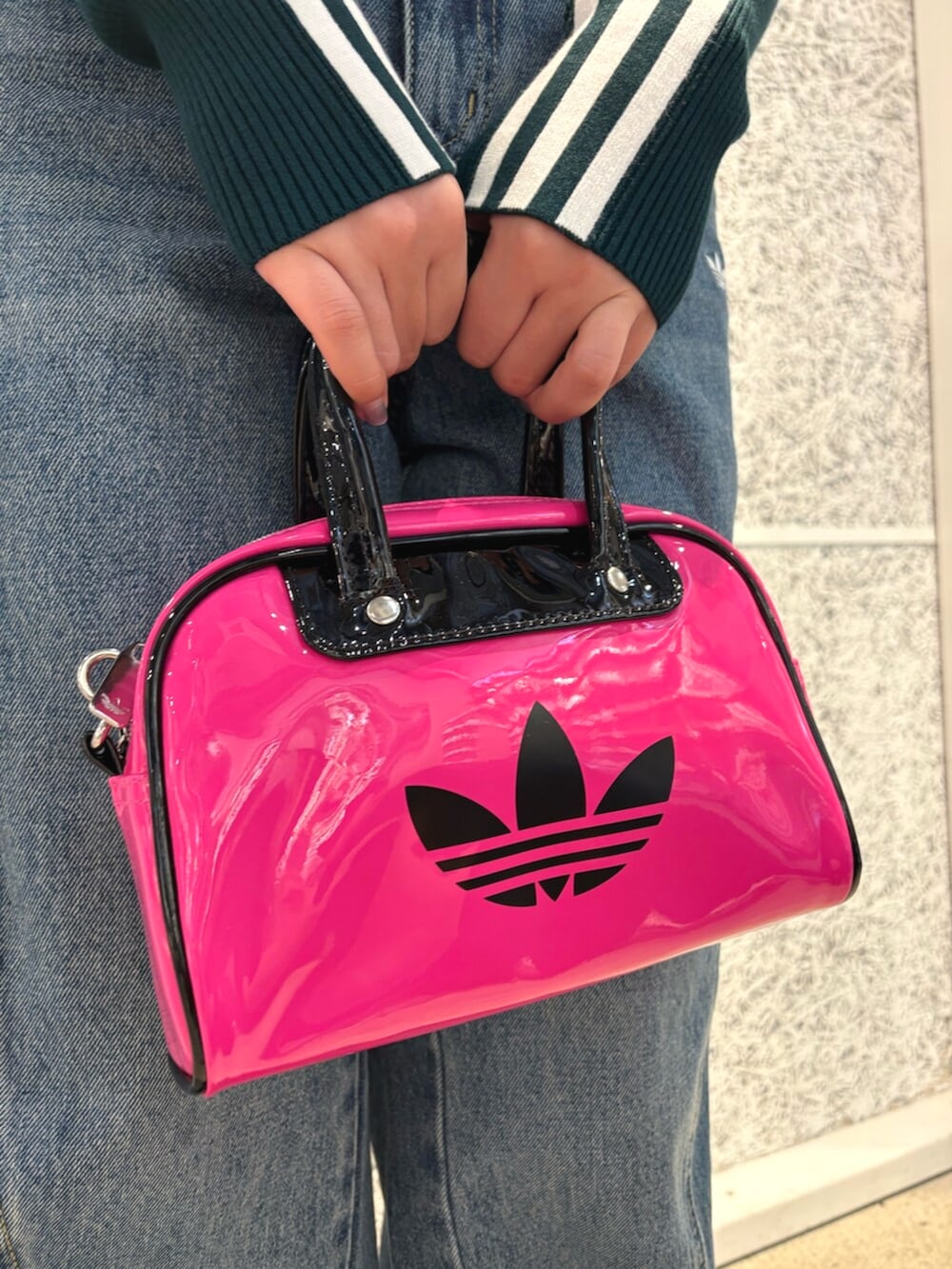 ピンク系のショルダーバッグ、グリーン系のニット/セーター、ブルー系のデニムパンツを着用したレディースの秋コーディネートの6枚目の写真