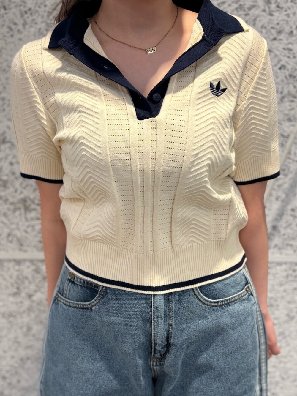 イエロー系のポロシャツ、ブルー系のデニムパンツ、ブラック系のシューズを着用したレディースの夏コーディネートの3枚目の写真