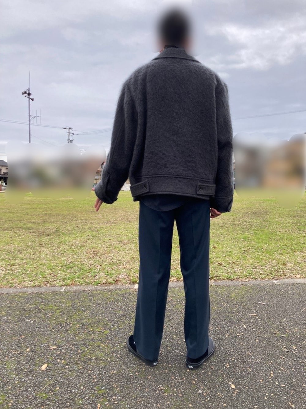 グレー系のブルゾン、ブルー系のスラックス、ブラック系のスニーカーを着用したメンズの冬コーディネートの3枚目の写真