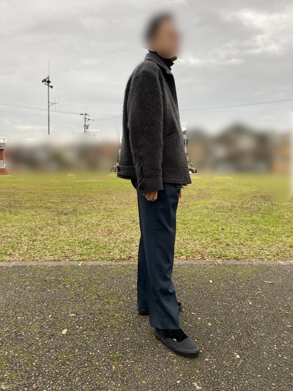 グレー系のブルゾン、ブルー系のスラックス、ブラック系のスニーカーを着用したメンズの冬コーディネートの2枚目の写真