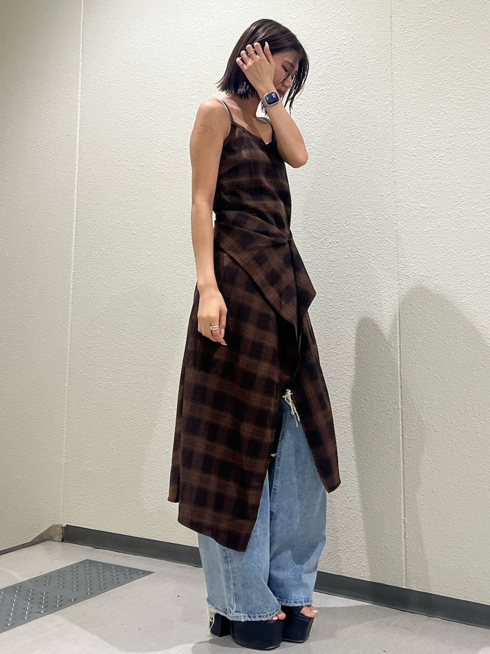 ブラウン系のワンピース、ブルー系のデニムパンツ、ブラック系のサンダルを着用したレディースの夏コーディネートの2枚目の写真