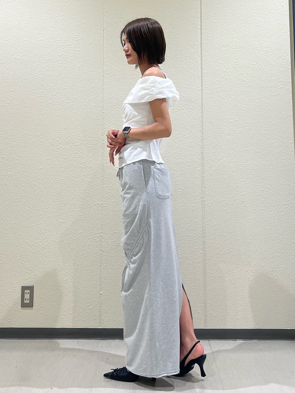 ホワイト系のTシャツ/カットソー、グレー系のスカート、ブラック系のパンプスを着用したレディースの夏コーディネートの2枚目の写真