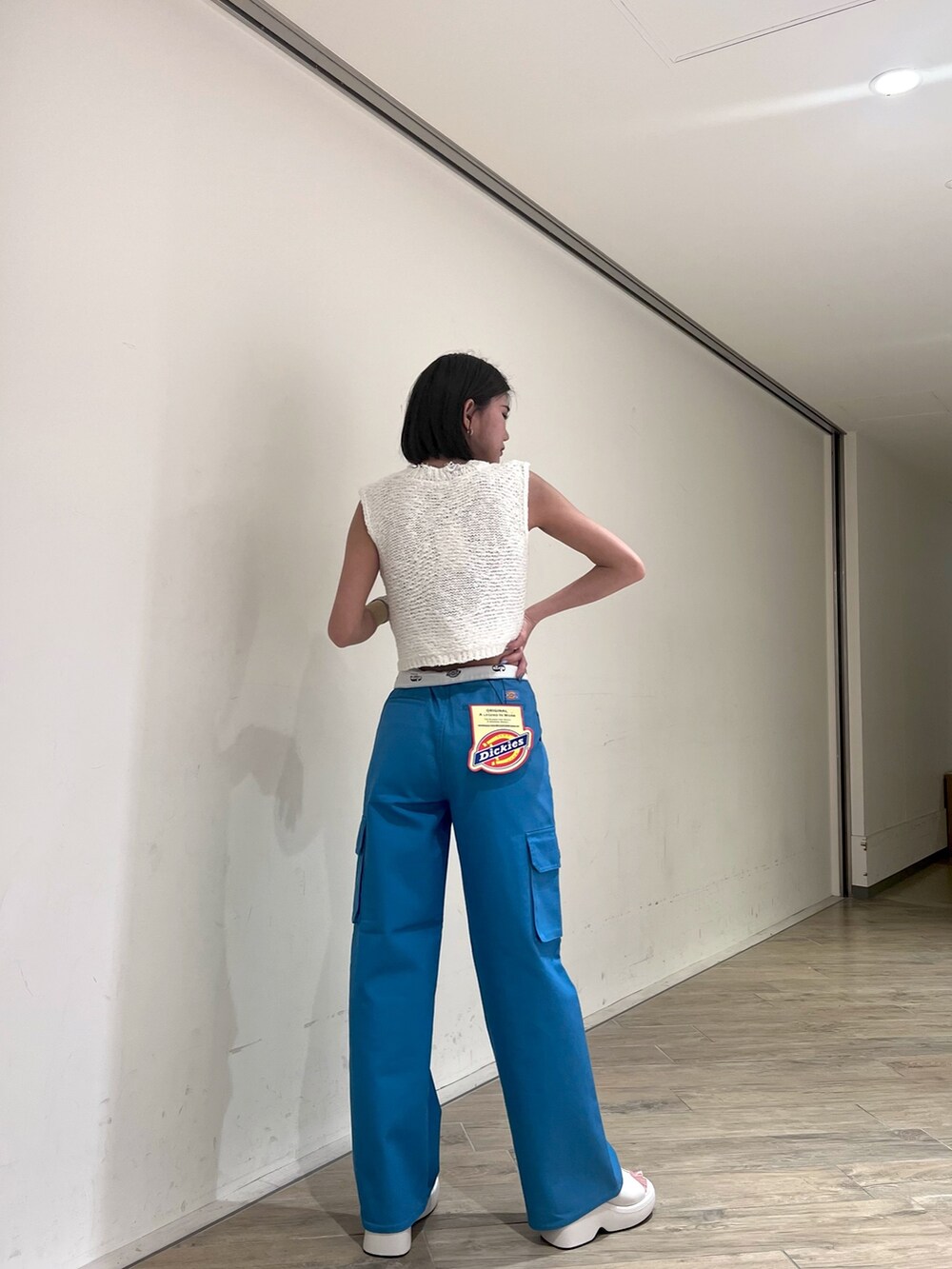 ホワイト系のベスト、ブルー系のカーゴパンツ、ホワイト系のサンダルを着用したレディースの夏コーディネートの3枚目の写真