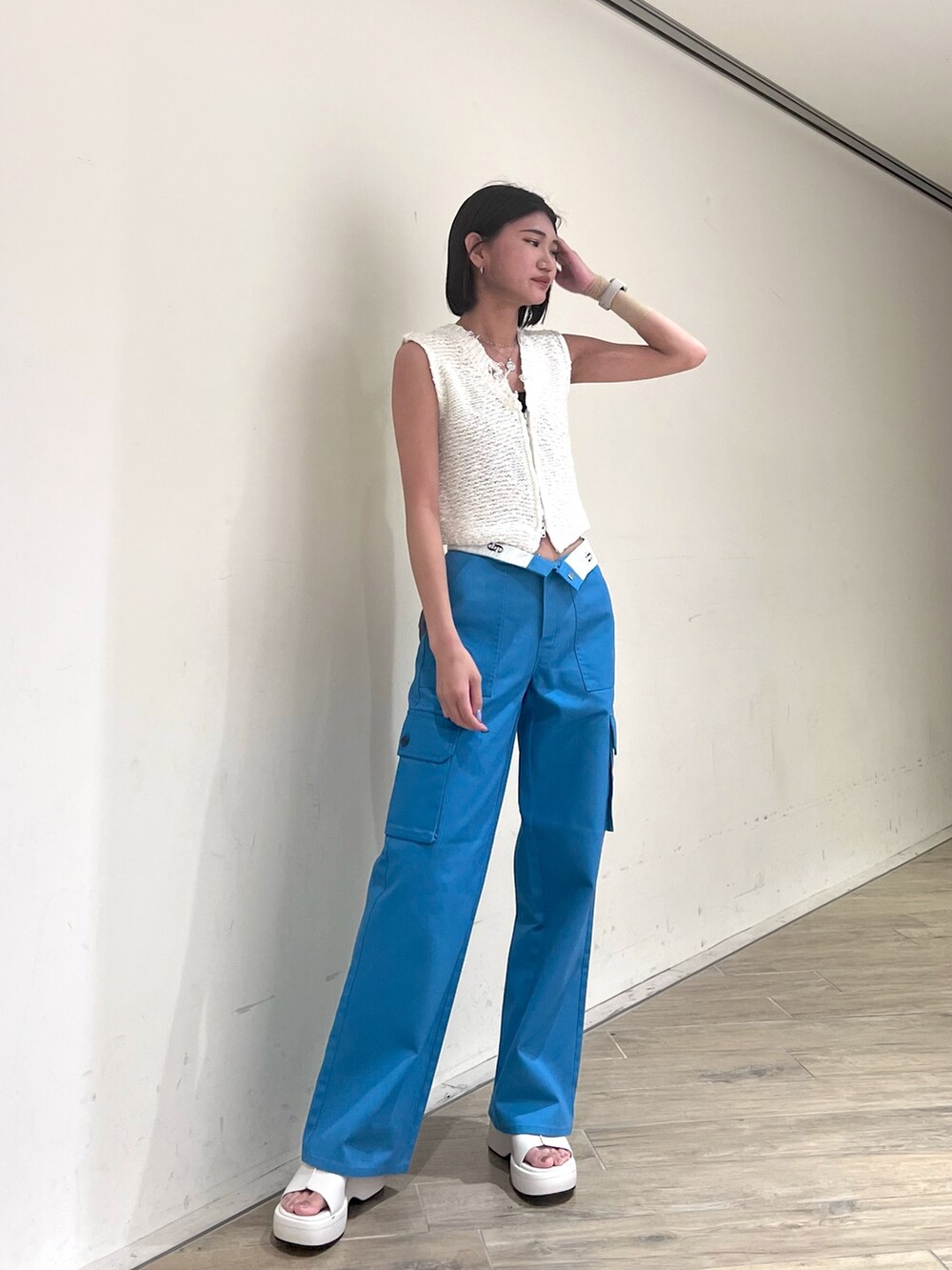 ホワイト系のベスト、ブルー系のカーゴパンツ、ホワイト系のサンダルを着用したレディースの夏コーディネートの2枚目の写真