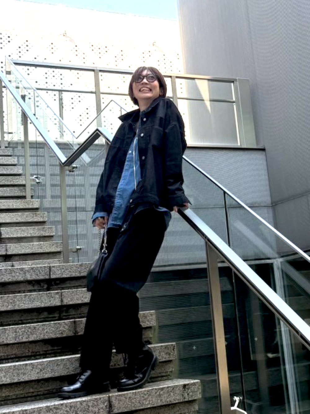 ブラック系のその他パンツ、ブラック系のブーツ、ブラック系のショルダーバッグを着用したレディースの春コーディネートの2枚目の写真