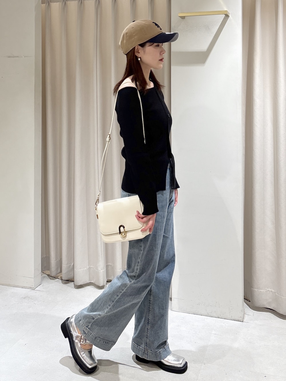 ブラック系のニット/セーター、ホワイト系のハンドバッグ、ブルー系のデニムパンツを着用したレディースの冬コーディネートの3枚目の写真