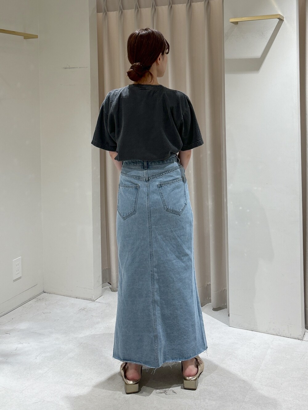 ブルー系のデニムスカート、ゴールド系のパンプス、ブラック系のTシャツ/カットソーを着用したレディースの春コーディネートの3枚目の写真