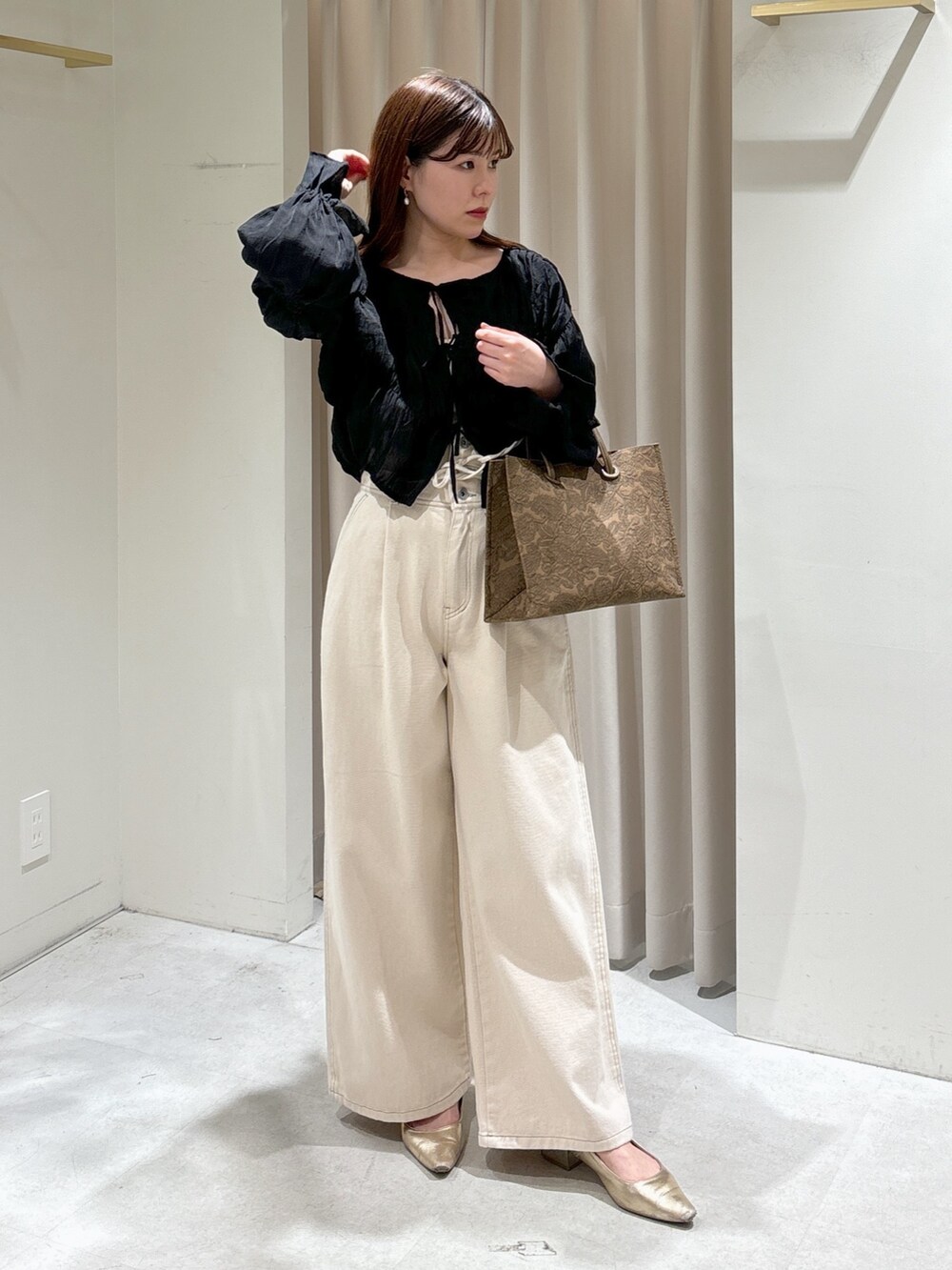 ブラウン系のトートバッグ、ホワイト系のデニムパンツ、ゴールド系のパンプスを着用したレディースの春コーディネートの5枚目の写真