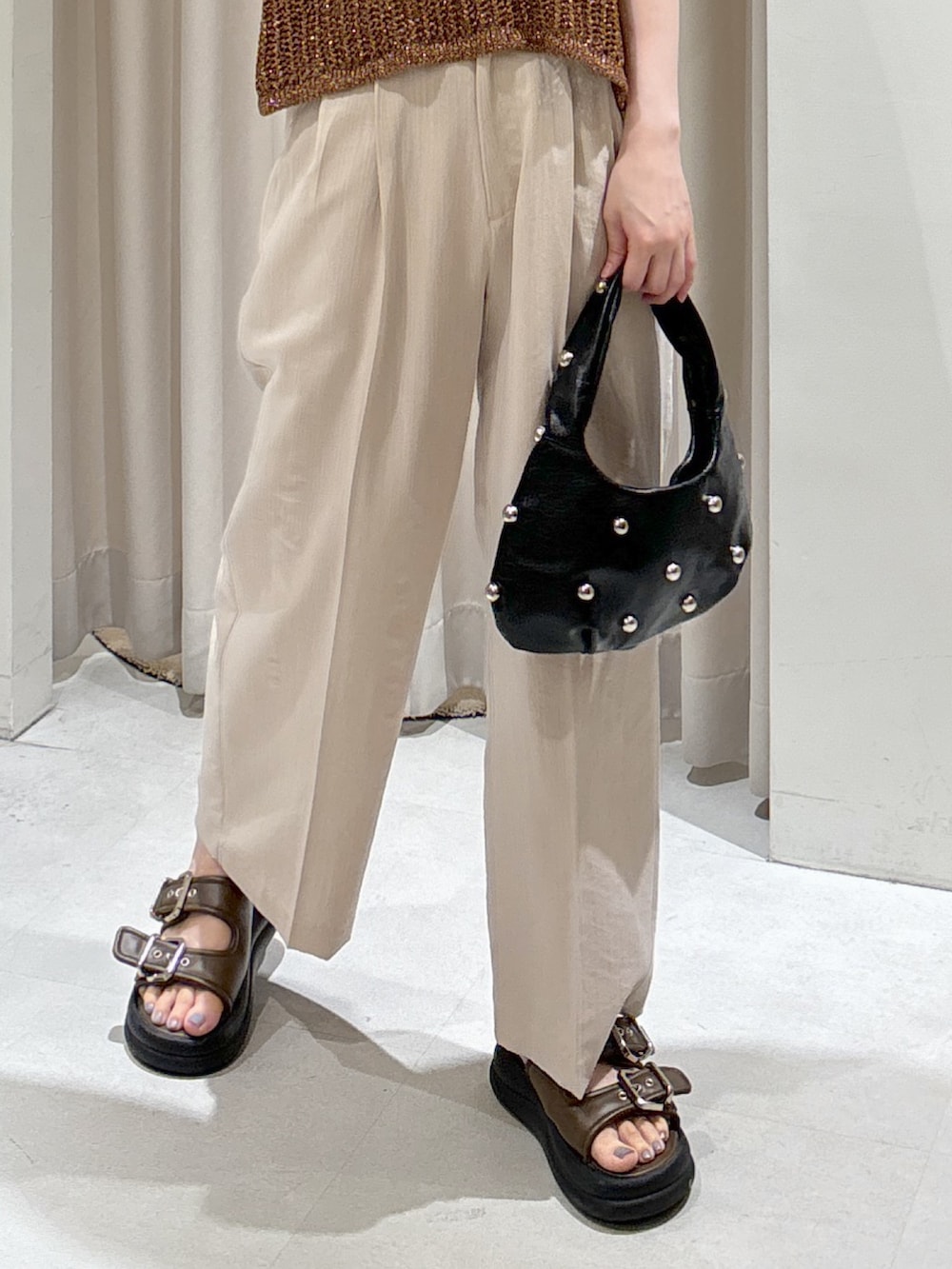 ブラウン系のベスト、ホワイト系のキャミソール、ブラック系のハンドバッグを着用したレディースの夏コーディネートの5枚目の写真