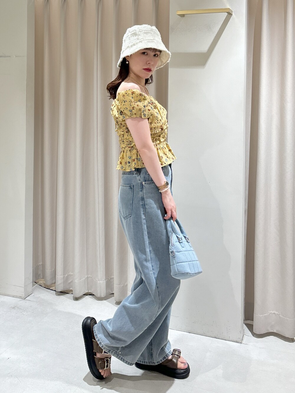 イエロー系のシャツ/ブラウス、ブルー系のトートバッグ、ブルー系のデニムパンツを着用したレディースの夏コーディネートの2枚目の写真