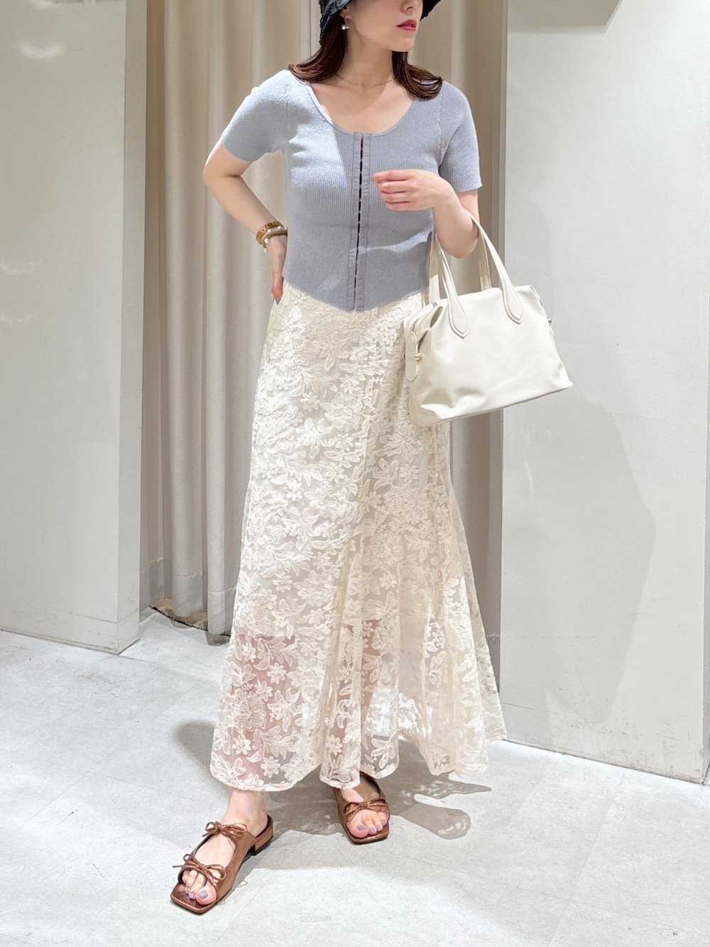 グレー系のニット/セーター、ホワイト系のスカート、ホワイト系のボストンバッグを着用したレディースの夏コーディネートの7枚目の写真