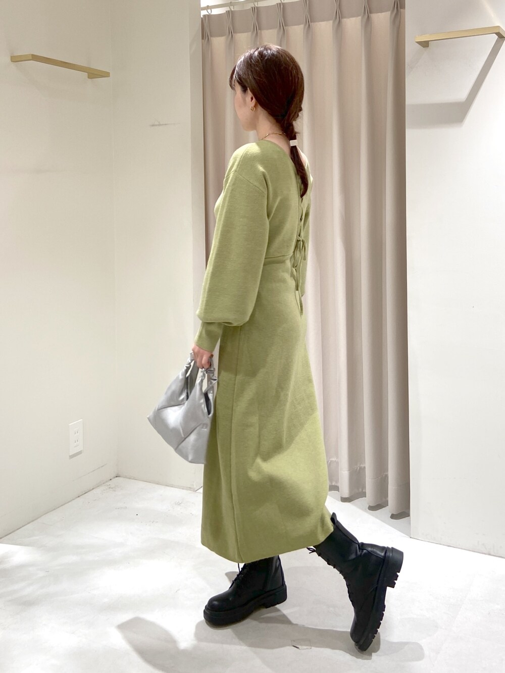 シルバー系のショルダーバッグ、ブラック系のブーツ、グリーン系のワンピースを着用したレディースの冬コーディネートの2枚目の写真