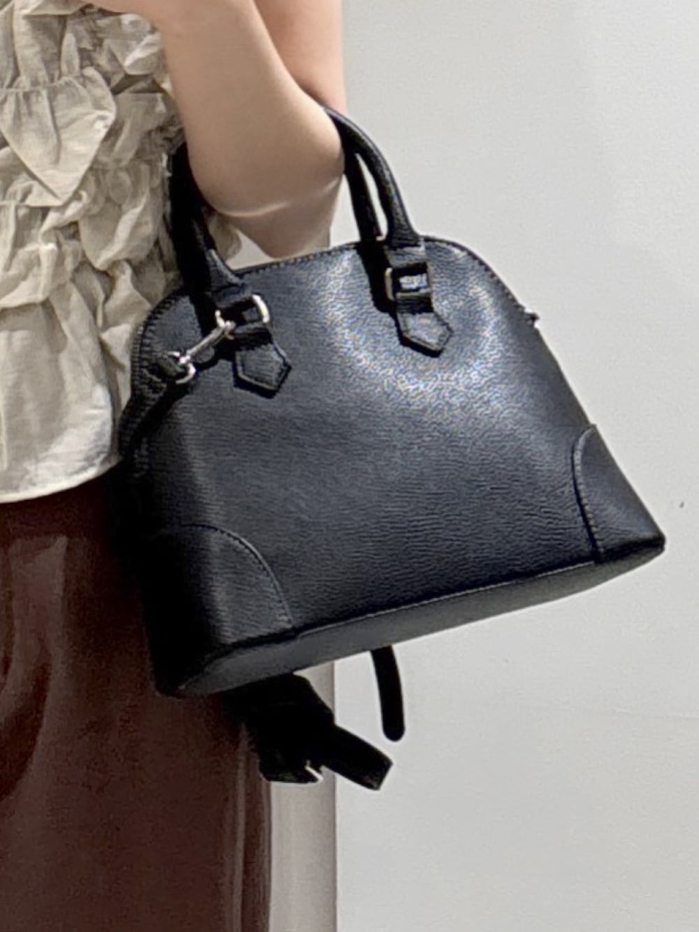 ブラウン系のデニムパンツ、ブラック系のショルダーバッグ、ブラック系のブーツを着用したレディースの秋コーディネートの6枚目の写真
