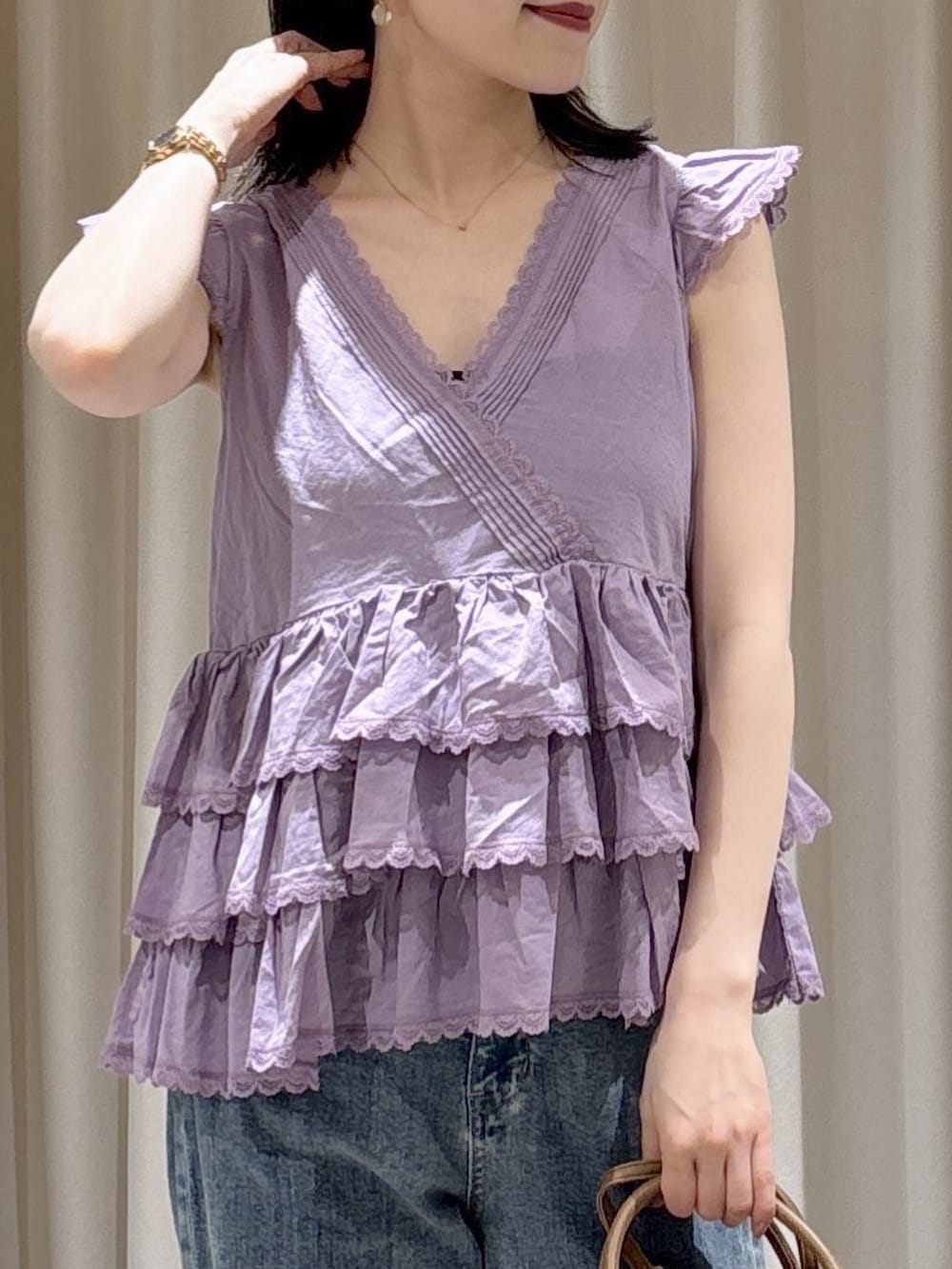 パープル系のシャツ/ブラウス、ブラウン系のハンドバッグ、ブルー系のデニムパンツを着用したレディースの夏コーディネートの4枚目の写真