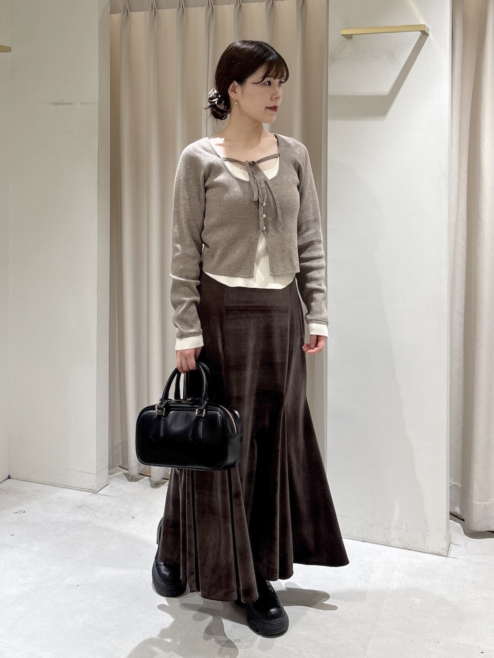 ブラウン系のニット/セーター、ブラウン系のスカート、ブラック系のブーツを着用したレディースの冬コーディネートの4枚目の写真