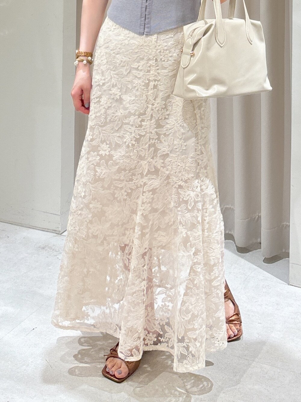 グレー系のニット/セーター、ホワイト系のスカート、ホワイト系のボストンバッグを着用したレディースの夏コーディネートの3枚目の写真