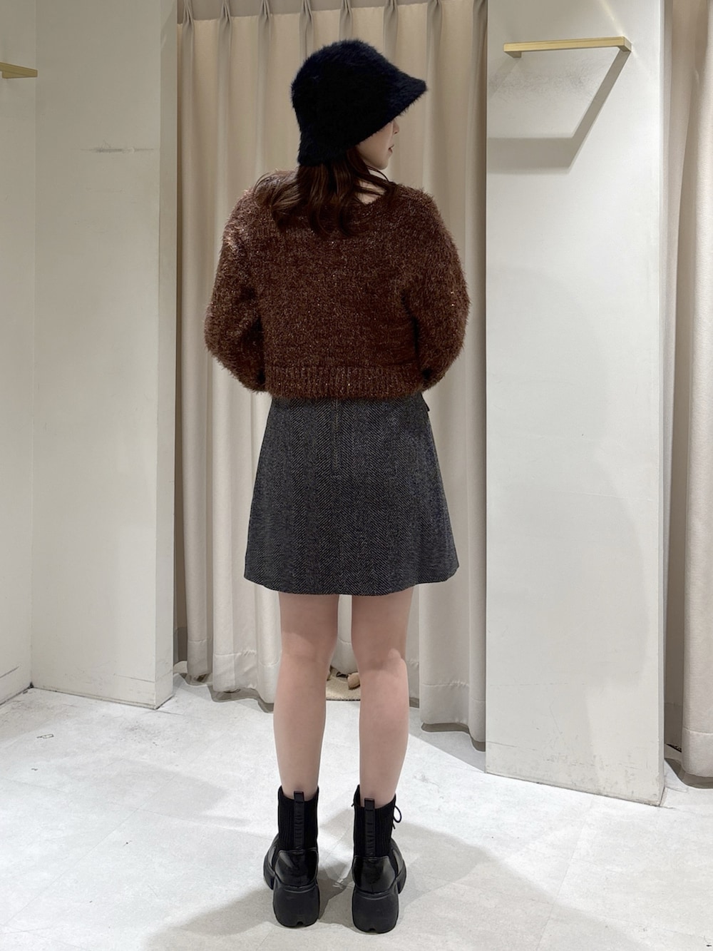 ブラウン系のニット/セーター、ブラック系のスカート、ブラック系のブーツを着用したレディースの冬コーディネートの3枚目の写真