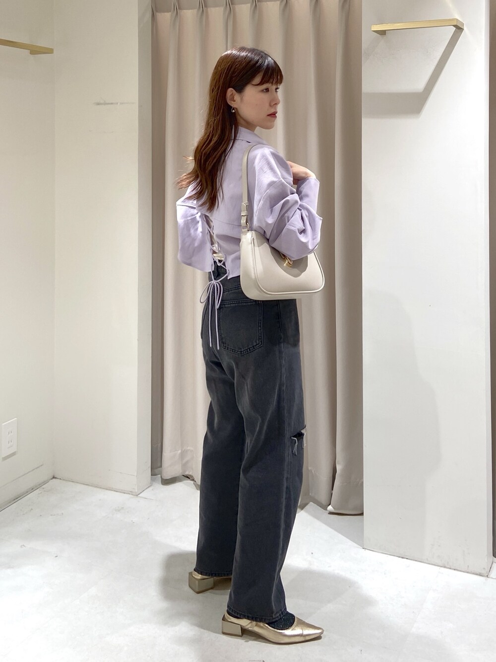 ブラック系のデニムパンツ、ゴールド系のパンプス、グレー系のショルダーバッグを着用したレディースの春コーディネートの5枚目の写真