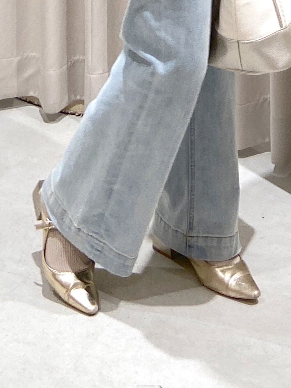 イエロー系のニット/セーター、シルバー系のトートバッグ、ブルー系のデニムパンツを着用したレディースの春コーディネートの5枚目の写真